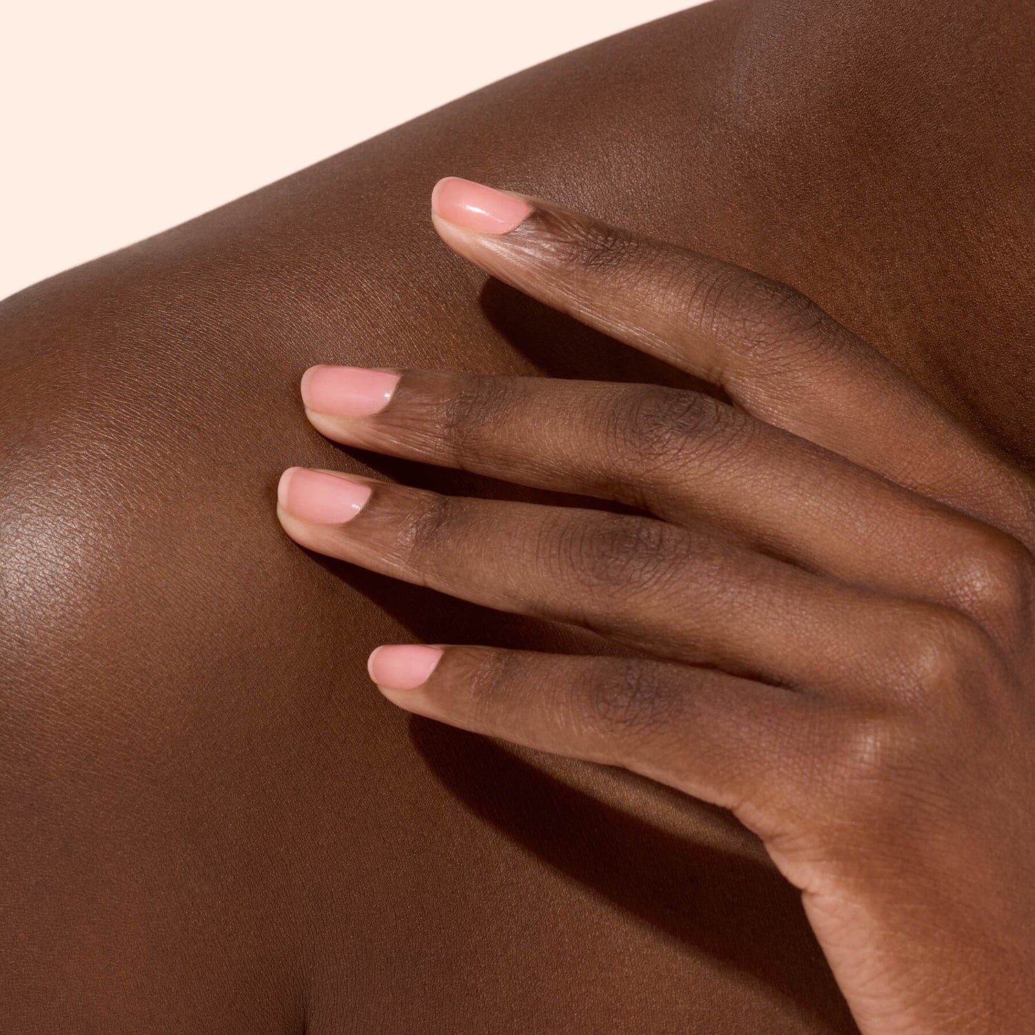 Main aux ongles rose doux sur épaule