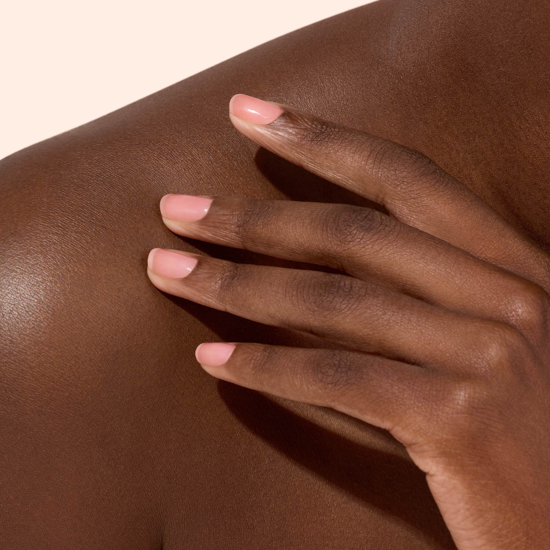 Main aux ongles rose doux sur épaule