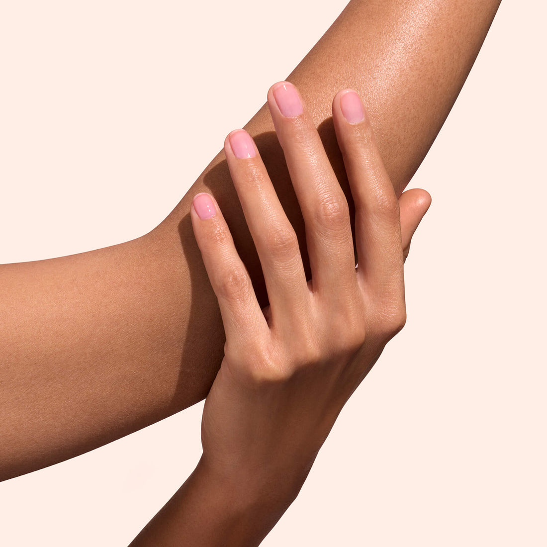 Main aux ongles rose translucide sur bras