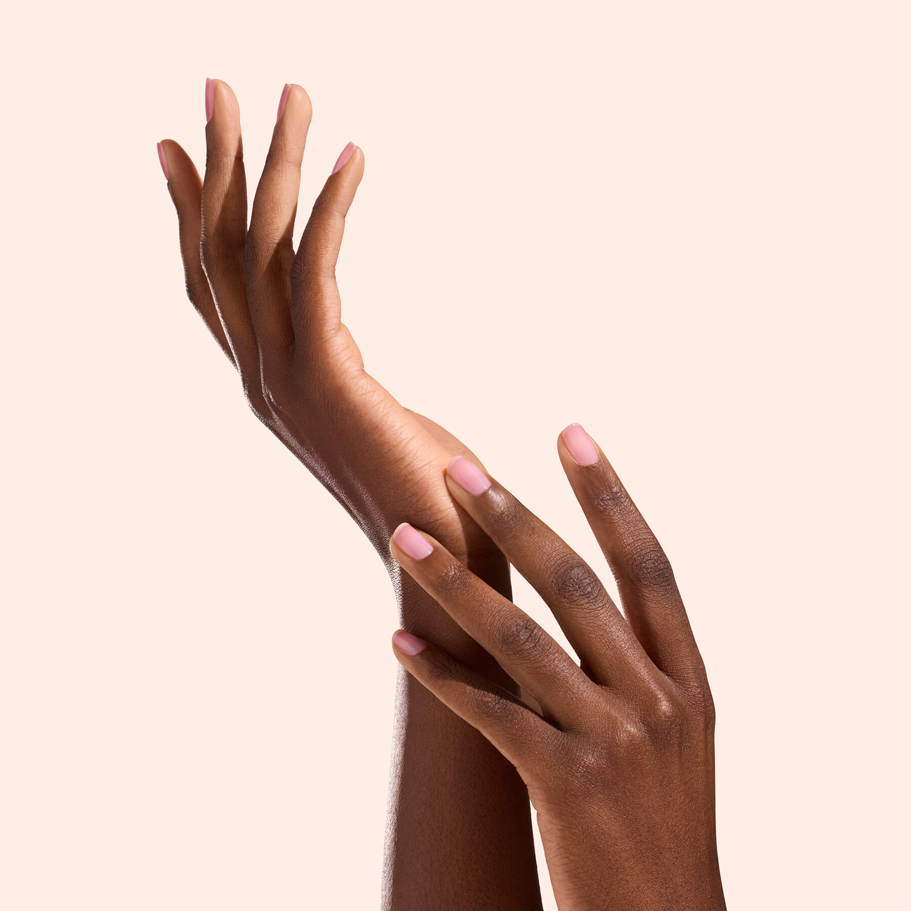 Deux mains aux ongles rose naturel