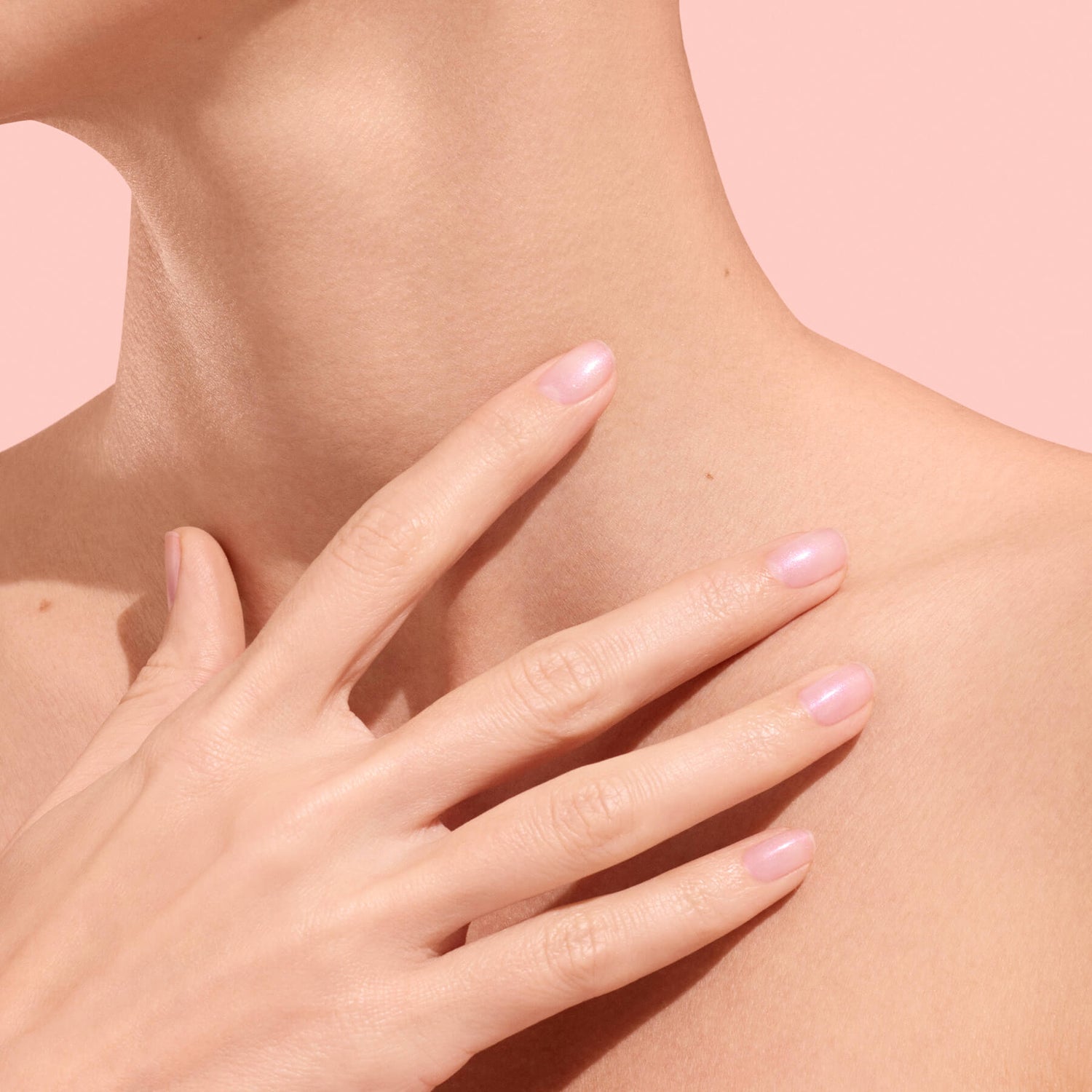 Main aux ongles rose translucide sur clavicule