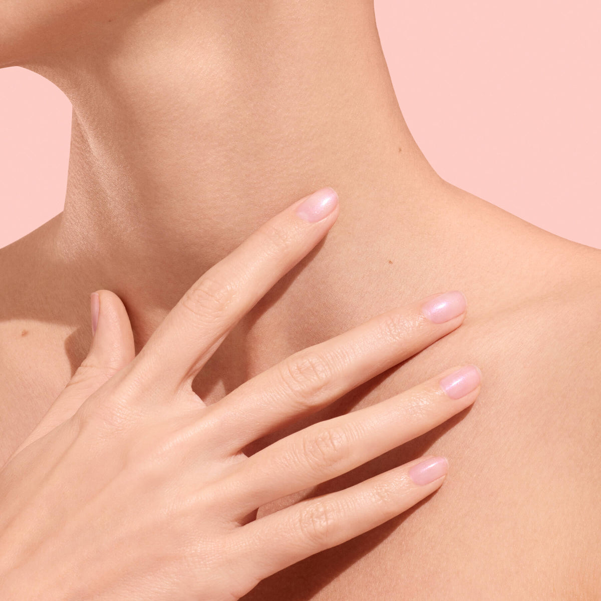 Mano con unghie rosa traslucide sulla clavicola