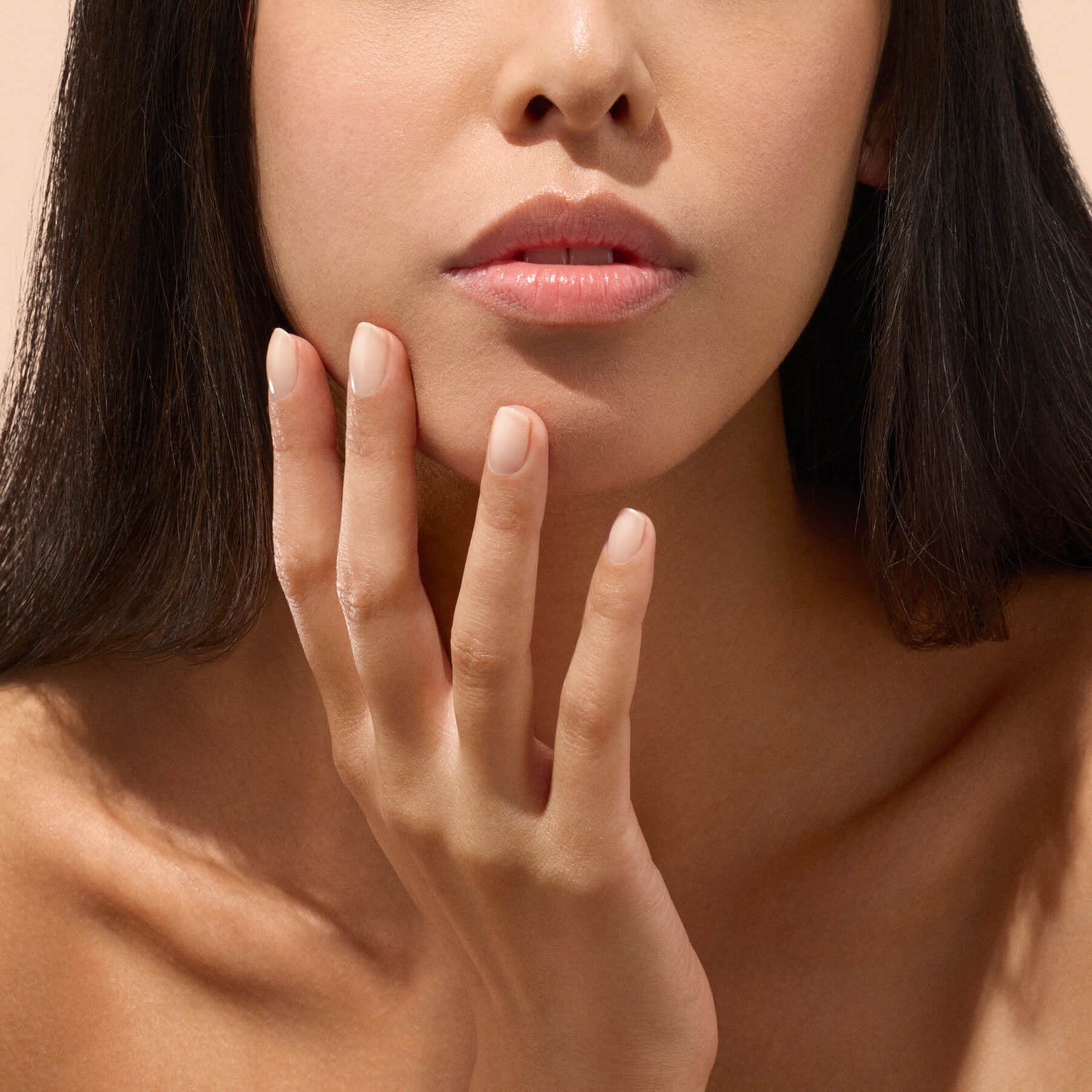 Main aux ongles naturels près de l’oreille