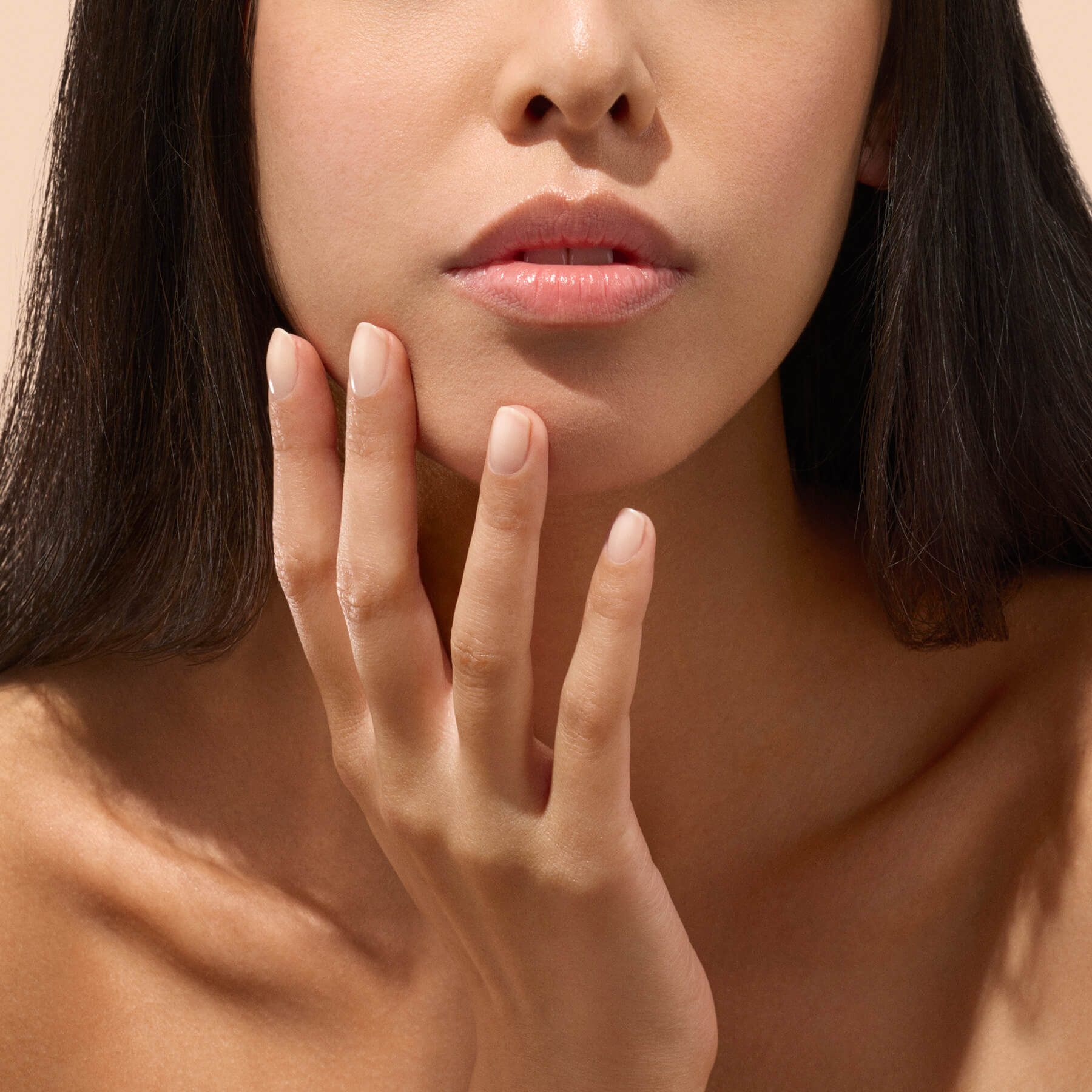 Main aux ongles naturels près de l’oreille