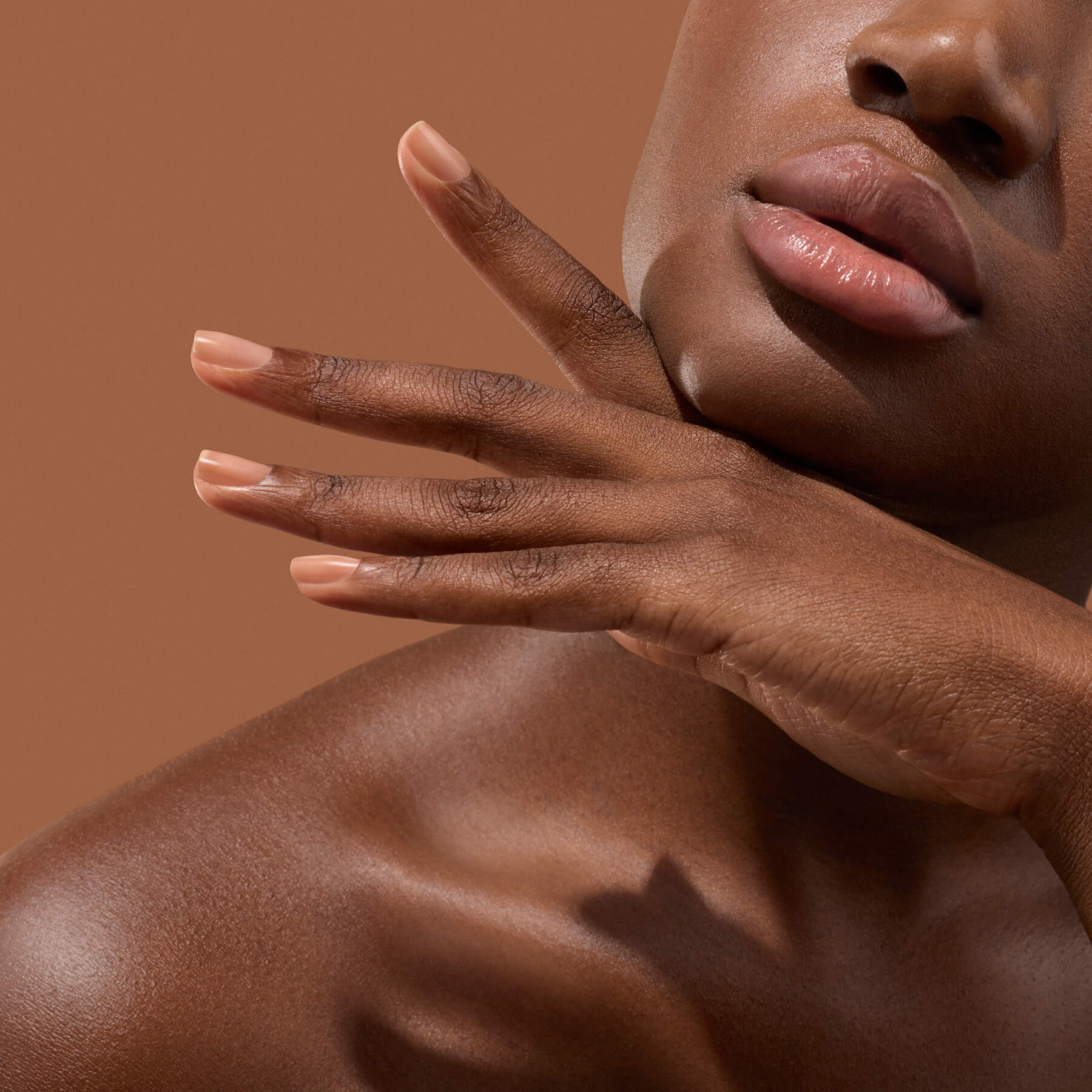 Main aux ongles beige sous le menton